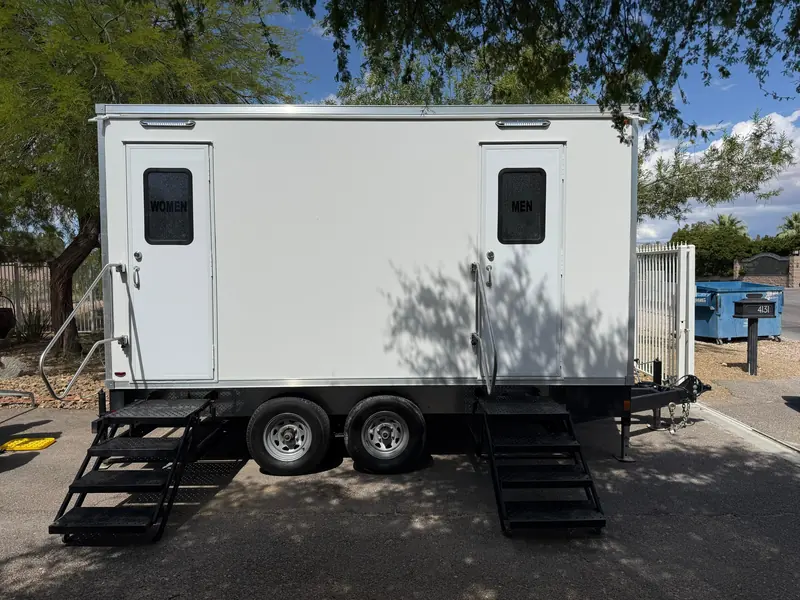 Two-stall portable restroom trailer on a paved driveway