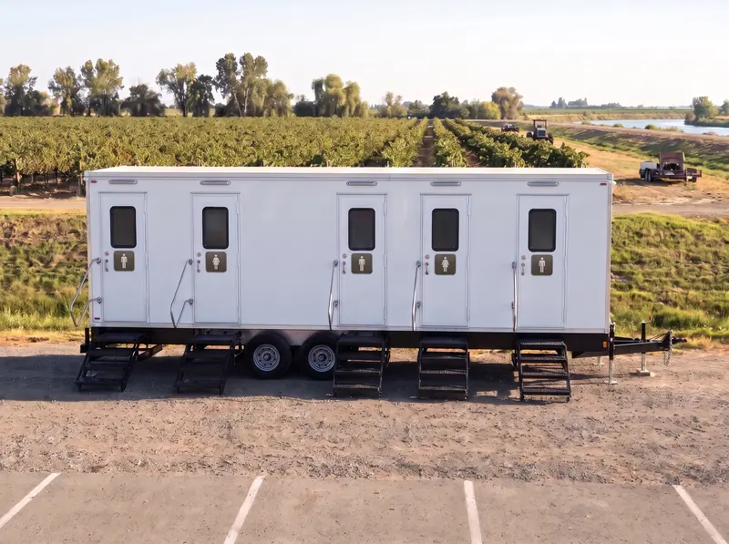 Large multi-stall restroom trailer on a stone patio