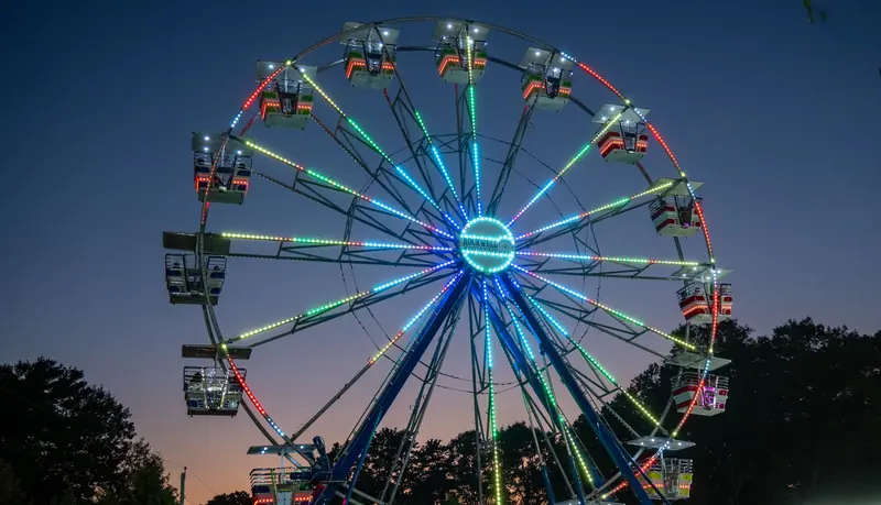 Lit Ferris wheel at a county fair at dusk