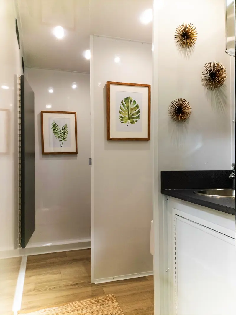 Bright hallway inside a restroom trailer with wall art and a vanity