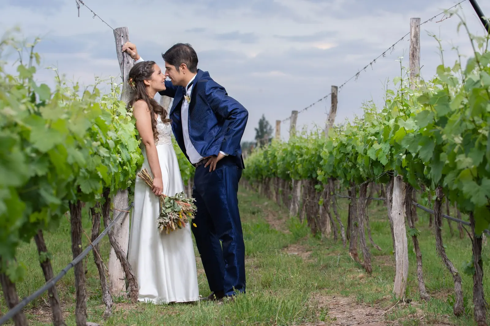Bride and groom sharing a moment between vineyard rows